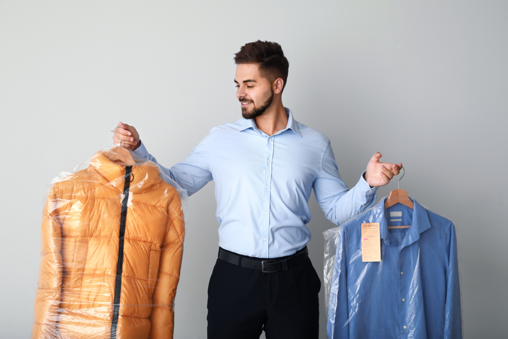 man holding dry cleaned clothing