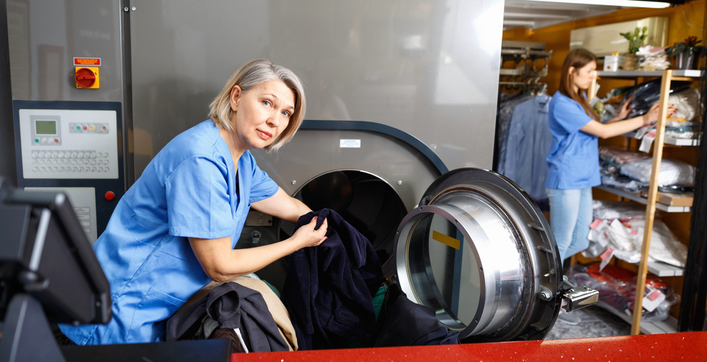 female worker taking out laundry from machine